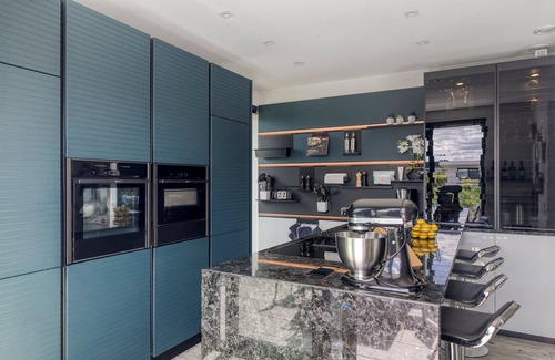 Zeewolde House | Detached 6-person villa by the water with a cosy living room featuring a piano and fireplace, modern kitchen with cooking island, and a sunny garden with lounge set.