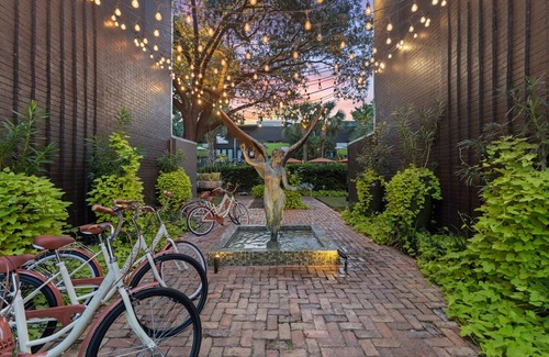 Lower Greenville Condo | Upscale 2BR Dallas condo with pool view and access to an award-winning courtyard featuring a resort-style pool, hot tub, dry sauna, and lush lounge areas. Enjoy a 77″ smart TV, sleek leather sofa, and modern kitchen for a stylish, comfortable stay.