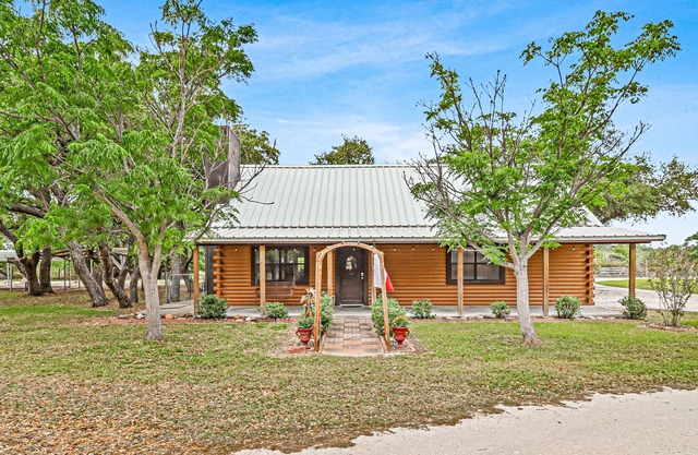 2-story cabin with an enclosed yard, patio, and large shade trees