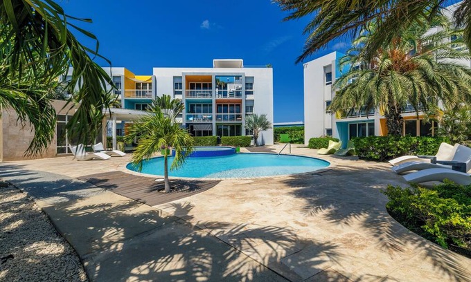 Boegoeroei Condo | Gated community with resort-style amenities - 2 bedroom, 2 bath with an open concept living room and kitchen. Private balcony overlooks pool area.